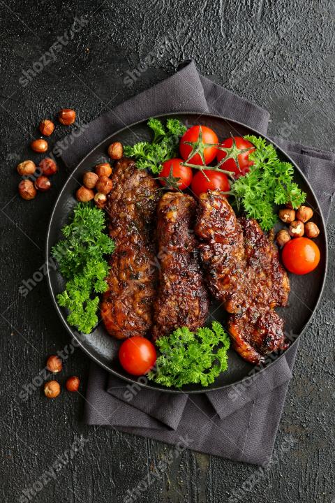 Succulent grilled meat served with fresh vegetables and herbs on a dark plate